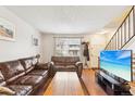 Inviting living room with a comfortable leather sofa, a bright window and staircase with natural light at 11228 W 18Th Ave, Lakewood, CO 80215