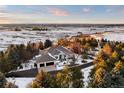 Stunning aerial view of a luxury home surrounded by lush greenery and snow covered fields in a serene setting at 7883 Fox Creek Trl, Franktown, CO 80116