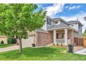 Beautifully landscaped front yard with a charming two-story home featuring a brick facade and a cozy front porch at 7472 S Memphis St, Aurora, CO 80016