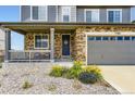 Close-up of front door with welcome sign, stone accents, and a colorful garden at 7360 S Old Hammer Way, Aurora, CO 80016
