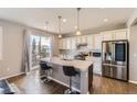 Bright kitchen with a central island, stainless steel appliances, and sliding glass doors to the deck at 7360 S Old Hammer Way, Aurora, CO 80016
