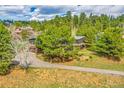 Aerial shot of a home nestled among lush green trees, with a winding driveway leading up to the house at 323 Paradise Rd, Golden, CO 80401