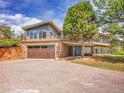 Home with wood garage door, stone facade, blue front door, second story deck, and a gravel driveway at 323 Paradise Rd, Golden, CO 80401