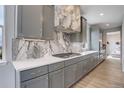 Elegant kitchen boasts gray cabinets, quartz countertops, a gas cooktop, and a stylish marble backsplash at 12917 Fox St, Westminster, CO 80234