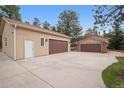 Large detached garage with multiple bays, brown doors, and expansive driveway at 30321 Chestnut Dr, Evergreen, CO 80439