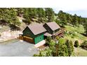 Aerial view of a green two-story home with a deck nestled among lush trees at 6066 Crawford Gulch Rd, Golden, CO 80403