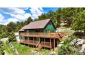 Green two-story home with a brown roof and a spacious wooden deck overlooking a green landscape at 6066 Crawford Gulch Rd, Golden, CO 80403
