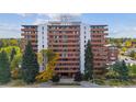 Exterior shot of a high-rise condo building with red brick and large balconies surrounded by mature trees at 4570 E Yale Ave # 706, Denver, CO 80222