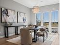 Elegant dining room with a modern chandelier, artwork, and scenic outdoor views through large windows at 5835 Chester Way, Denver, CO 80238