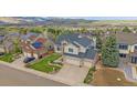 An aerial view showcases the home's roof, three car garage, and landscaping in a scenic neighborhood at 15887 W Ellsworth Ln, Golden, CO 80401