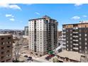 An exterior, high-angle view of the condo building against a mountain backdrop and street-level parking at 2 Adams St # 806, Denver, CO 80206