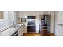 Bright kitchen features white cabinets, granite countertops, stainless steel appliances, and hardwood floors at 1050 S Monaco Pkwy # 38, Denver, CO 80224