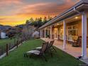 Backyard featuring green lawn, a covered patio with seating, and scenic views of the surrounding landscape at sunset at 2571 Sw Grapevine Rd, Idledale, CO 80453