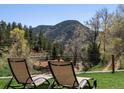 Relaxing backyard view with lounge chairs overlooking the lush greenery and mountain scenery at 2571 Sw Grapevine Rd, Idledale, CO 80453