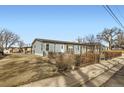 Exterior view of a charming light blue home with a picket fence and quaint landscaping at 441 Johnson St, Frederick, CO 80530
