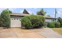 A driveway leading to an attached garage with mature landscaping in the front yard at 9590 Lowell Blvd, Westminster, CO 80031