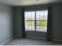 Carpeted bedroom features neutral walls, large window with curtains, and exterior views at 12304 W Cross Dr # 304, Littleton, CO 80127