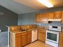 Bright kitchen with granite countertops, oak cabinets, stainless steel sink and white appliances at 12304 W Cross Dr # 304, Littleton, CO 80127
