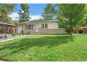 Inviting single-story home with green lawn, landscaping, and brick accents at 6147 Jellison Way, Arvada, CO 80004