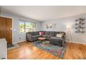 Cozy living room featuring hardwood floors, a gray sectional, and a large window at 6147 Jellison Way, Arvada, CO 80004