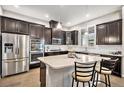 Modern kitchen boasts stainless steel appliances, a large island, and dark cabinets with updated lighting at 24943 E Phillips Pl, Aurora, CO 80016
