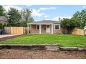 Charming single-story home featuring a covered porch, well-maintained lawn, and a rustic wooden retaining wall at 1865 S Knox Ct, Denver, CO 80219