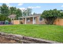 Charming single-story home featuring a covered porch, well-maintained lawn, and a rustic wooden retaining wall at 1865 S Knox Ct, Denver, CO 80219