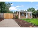 This charming home boasts a spacious driveway and a well-manicured lawn, enhanced by a stylish, light-colored fence at 1865 S Knox Ct, Denver, CO 80219
