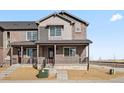 Well-maintained townhome featuring a covered front porch, complemented by brick and siding accents at 6504 N Malaya St, Aurora, CO 80019