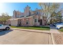 Exterior view of condo featuring brick and tan siding, chimney, designated parking, and well-maintained landscaping at 4931 Garrison St # 204G, Wheat Ridge, CO 80033
