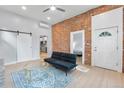Bright living area with exposed brick wall, ceiling fan, and an open doorway to the bedroom at 2737 N Marion St, Denver, CO 80205