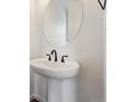 Close up of a pedestal sink with an oval mirror in a bathroom at 9237 Truckee Ct, Commerce City, CO 80022
