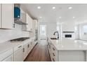 Bright kitchen features white cabinets, long island, and stainless steel appliances at 9237 Truckee Ct, Commerce City, CO 80022