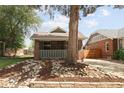 Quaint brick home with a covered porch, rock garden, and mature tree in front at 3039 W Denver Pl, Denver, CO 80211