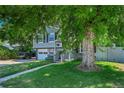 Home with gray siding, dark shutters, yellow door, mature trees, and a well-manicured yard at 8710 Alta Vista Dr, Arvada, CO 80004