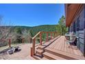 A spacious wooden deck with mountain views, seating area, and a fire pit for outdoor enjoyment at 617 Hummingbird Trl, Idaho Springs, CO 80452