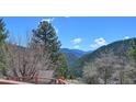 A scenic view of mountains and sky with a lush green canopy of trees at 617 Hummingbird Trl, Idaho Springs, CO 80452