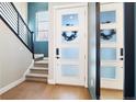 Inviting entryway featuring a staircase with metal railing, modern front door with glass panels, and light wood flooring at 1565 W 67Th Ave, Denver, CO 80221