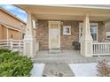 Inviting covered front porch with brick accents and a seating area to enjoy the outdoors. Address is visible at 23601 E Mississippi Cir, Aurora, CO 80018