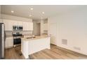 Well-lit kitchen featuring an island, quartz countertops and modern appliances at 15228 Detroit St, Thornton, CO 80602