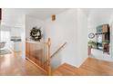 Bright hallway with hardwood floors, a wooden banister, and a view of the kitchen and living area at 23753 E 155Th Way, Brighton, CO 80603