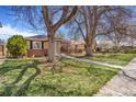 Attractive home featuring a well-maintained lawn, mature trees, and a walkway at 3254 S Bannock St, Englewood, CO 80110
