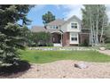 Beautiful two-story home with a well-manicured lawn, stone accents, and mature trees at 8389 Owl Roost Ct, Parker, CO 80134