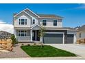 Two-story home with light gray siding, stone accents, a three-car garage, a manicured lawn and a charming front porch at 39141 Anthony St, Elizabeth, CO 80107