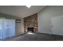 View of the carpeted living room featuring a large stone fireplace, a skylight, and access to a sliding glass door at 10150 E Virginia Ave # 308, Denver, CO 80247