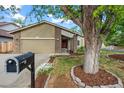 Inviting exterior with a charming front yard, a two-car garage, and mature tree at 2090 S Fairplay St, Aurora, CO 80014