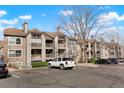 A view of multiple condo units, each with a balcony, surrounded by parking and mature trees at 9212 E Arbor Cir # E, Englewood, CO 80111