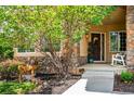 Inviting front porch with stone accents, a rocking chair, and lush landscaping at 5368 Wildcat Ct, Morrison, CO 80465