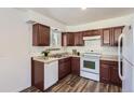 Well-lit kitchen featuring wood cabinets, standard appliances, a double-basin sink, and wood-look floors at 2060 W Iliff Ave, Englewood, CO 80110