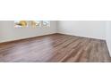 Bright, empty bedroom with wood-look flooring and large, light-filled windows at 9852 Cathay St, Commerce City, CO 80022
